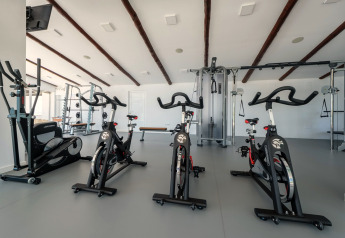 Salle de sport moderne dans un hébergement glamping avec vélos d'appartement et machines de musculation.