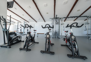 Moderne fitnesscenter på glamping med motionscykler, styrketræningsudstyr og store vinduer.