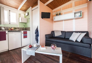 Gemütlicher Bungalow mit Sofa, Küchenzeile und Fernseher im Camping Estival Torre de la Mora, Spanien.
