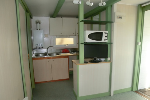 Pequeña cocina con fregadero, microondas y televisión en Camping Cambrils Playa 1 Bungalow Oasis, España.