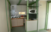 Pequeña cocina con fregadero, microondas y televisión en Camping Cambrils Playa 1 Bungalow Oasis, España.