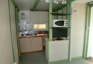 Pequeña cocina con fregadero, microondas y televisión en Camping Cambrils Playa 1 Bungalow Oasis, España.