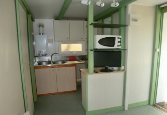 Pequeña cocina con fregadero, microondas y televisión en Camping Cambrils Playa 1 Bungalow Oasis, España.