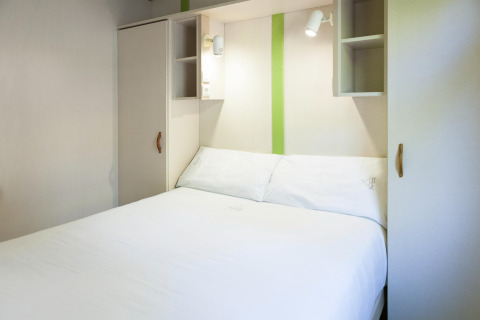 Moderne slaapkamer bij Camping Cambrils Playa 2 BUNGALOW PREMIUM in Spanje met wit bed en kasten.