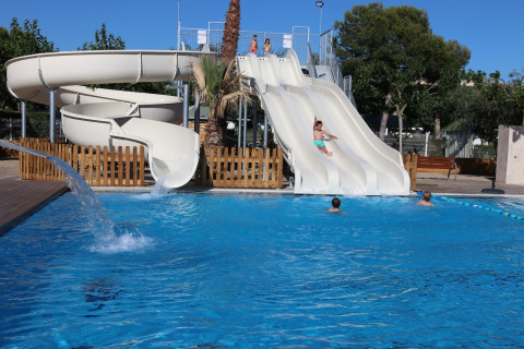 Zona de piscina exterior con toboganes y niños jugando en Camping Cambrils Playa 1 BUNGALOW OASIS, España.