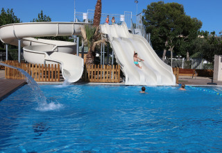 Zona de piscina exterior con toboganes y niños jugando en Camping Cambrils Playa 1 BUNGALOW OASIS, España.