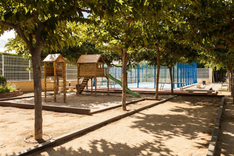 Parque infantil con estructura de madera y tobogán en Camping Cambrils Playa 1 BUNGALOW OASIS, España, rodeado de árboles.