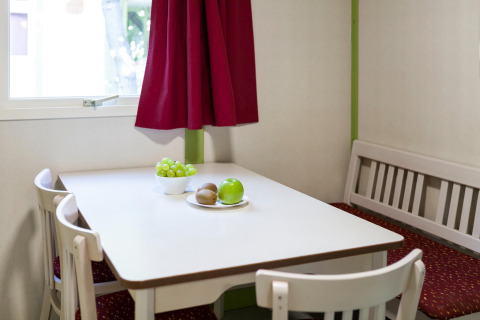 Gezellige eethoek in Camping Cambrils Playa 2 Bungalow Premium in Spanje, met fruit op de tafel bij het raam.