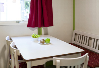 Acogedor comedor en Camping Cambrils Playa 2 Bungalow Premium, España, con fruta en la mesa cerca de la ventana.