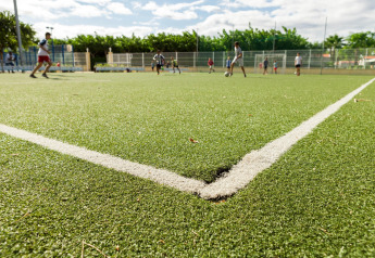 Kinderen spelen voetbal op een kunstgrasveld bij een outdoor glamping accommodatie.