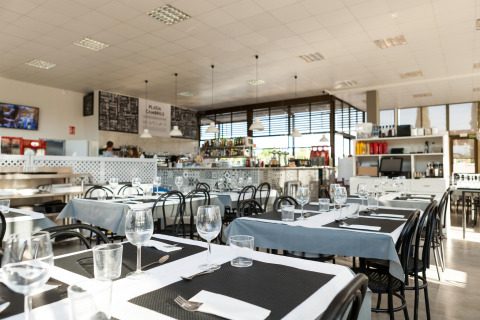 Foto af en moderne restaurant med dækkede borde og store vinduer på et glamping opholdssted.