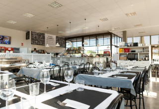 Interior de restaurante moderno con mesas preparadas en un alojamiento de glamping iluminado y amplio.