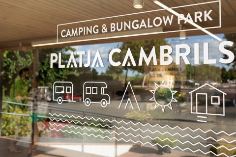 Entrada a Camping & Bungalow Park Platja Cambrils con iconos de caravana, tienda, sol y bungalow visibles.