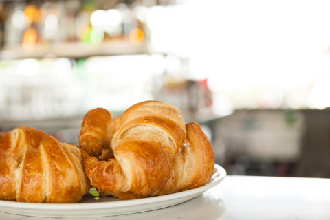 Friske croissanter på en tallerken serveret på et glampingsted med sløret baggrund i dagslys.