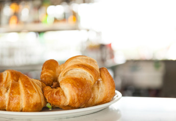 Croissants frescos en un plato servidos en un alojamiento glamping con fondo borroso y luminoso.