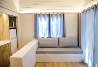Lyst og moderne opholdsområde i La Llosa 1 Xaloc-lodgen i Spanien med sofa, gardiner og tekøkken.