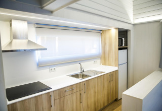 Moderne køkken i lodge «La Llosa 1 Xaloc», Spanien med træskabe, elektrisk komfur og stort vindue.