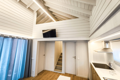 Indretning af moderne lodge ‘La Llosa 1 Xaloc’ i Spanien, med trægulve, køkken og opholdsstue.