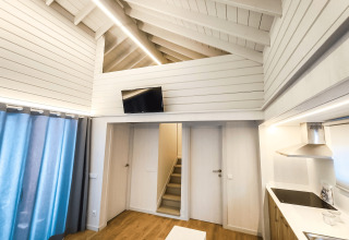 Indretning af moderne lodge ‘La Llosa 1 Xaloc’ i Spanien, med trægulve, køkken og opholdsstue.