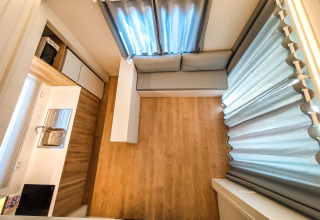 Fugleperspektiv af en moderne, kompakt lodge med køkkenhjørne, sofa og store vinduer i Spanien.