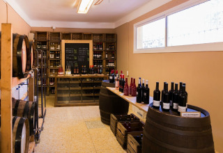 Magasin de vins avec tonneaux, bouteilles et étagères dans un hébergement glamping bien éclairé.