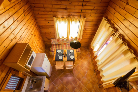 Luftfoto af et hyggeligt træindrettet lodge La Llosa 1 Xaloc i Spanien med spiseområde og lille køkken.