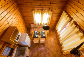 Luftfoto af et hyggeligt træindrettet lodge La Llosa 1 Xaloc i Spanien med spiseområde og lille køkken.