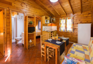 Intérieur de cabane en bois à La Llosa Ponent, Espagne, avec coin repas, cuisine, salle de bain et chambre.