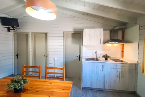 Intérieur lumineux d’un lodge à La Llosa Ponent en Espagne avec coin cuisine, table, et trois portes.