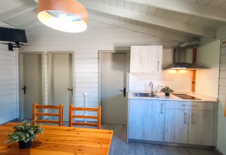 Intérieur lumineux d’un lodge à La Llosa Ponent en Espagne avec coin cuisine, table, et trois portes.