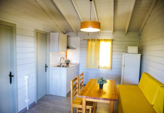 Intérieur douillet d’un lodge à La Llosa Ponent, Espagne, avec cuisine, table à manger et canapé jaune.