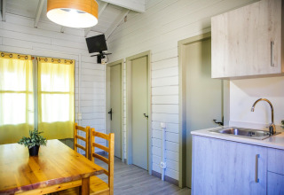 Intérieur du lodge La Llosa Ponent en Espagne avec table à manger, kitchenette, portes et téléviseur.