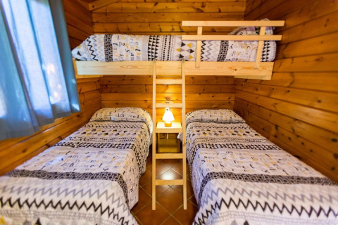Chambre à La Llosa Ponent en Espagne avec deux lits simples et un lit superposé dans un chalet en bois.