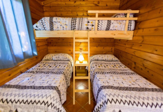 Chambre à La Llosa Ponent en Espagne avec deux lits simples et un lit superposé dans un chalet en bois.