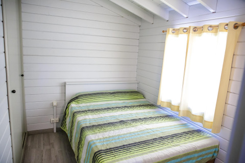 Chambre lumineuse et chaleureuse avec lit double et couvre-lit rayé à La Llosa Ponent, en Espagne.