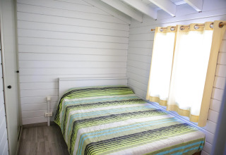Chambre lumineuse et chaleureuse avec lit double et couvre-lit rayé à La Llosa Ponent, en Espagne.