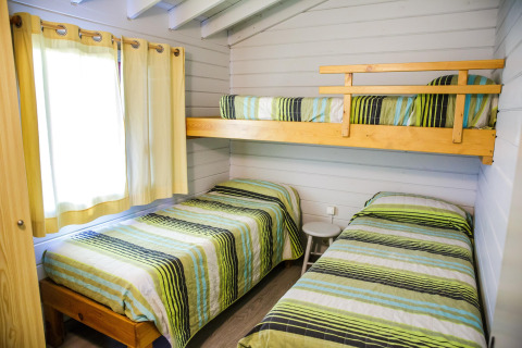 Chambre avec trois lits simples dont une mezzanine, couvertures rayées, La Llosa Ponent, Espagne.