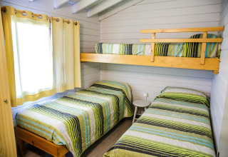 Chambre avec trois lits simples dont une mezzanine, couvertures rayées, La Llosa Ponent, Espagne.