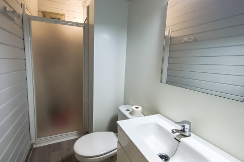 Salle de bain de la cabane La Llosa Ponent en Espagne avec douche, toilettes, lavabo et miroir.