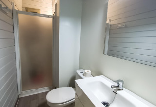 Salle de bain de la cabane La Llosa Ponent en Espagne avec douche, toilettes, lavabo et miroir.