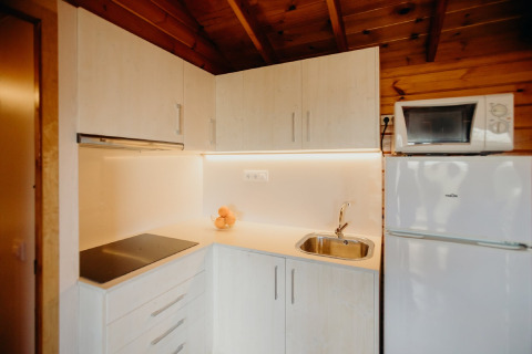 Cucina moderna nella cabina La Llosa 3 LLEBEIG in Spagna con mobili bianchi, piano cottura e frigorifero.
