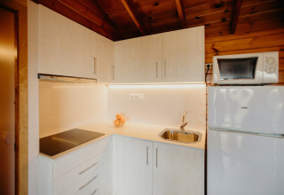 Cucina moderna nella cabina La Llosa 3 LLEBEIG in Spagna con mobili bianchi, piano cottura e frigorifero.