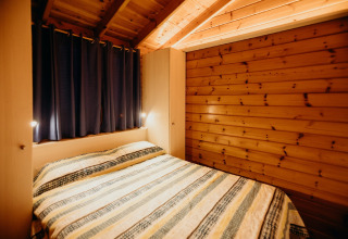 Accogliente camera in legno con soffitto inclinato, letto matrimoniale e tende scure a La Llosa 3 LLEBEIG, Spagna.