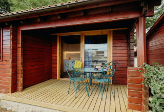Baita in legno con veranda e sedie verdi, foto scattata a La Llosa 3 LLEBEIG in Spagna.