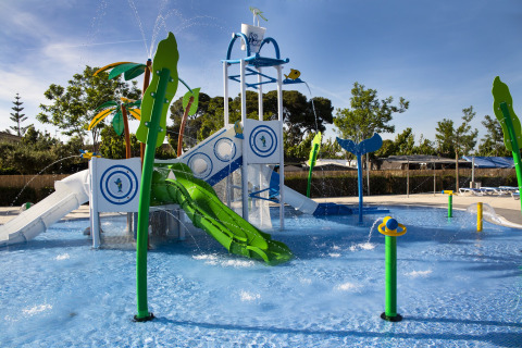 Aire de jeux aquatique avec toboggans et jets d'eau dans une zone de lodge familiale par beau temps.
