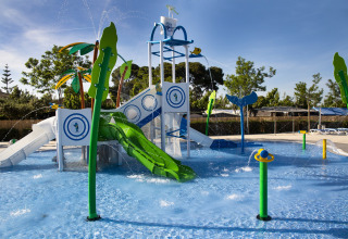 Aire de jeux aquatique avec toboggans et jets d'eau dans une zone de lodge familiale par beau temps.