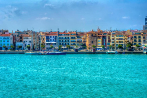 Vue colorée du front de mer depuis le lodge La Llosa Ponent en Espagne avec voiliers et bâtiments.