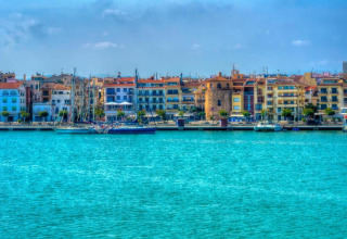 Vue colorée du front de mer depuis le lodge La Llosa Ponent en Espagne avec voiliers et bâtiments.