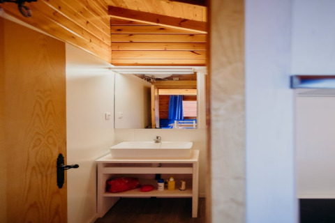 Vista di un bagno con soffitto in legno e specchio nella cabina La Llosa 3 LLEBEIG in Spagna.