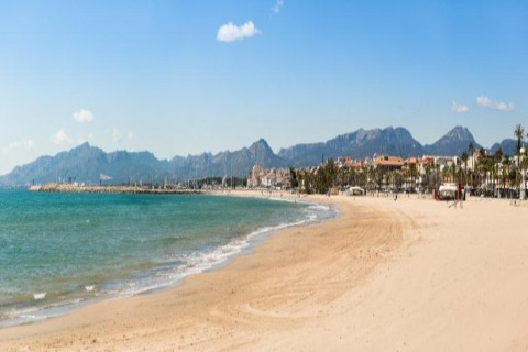 Vue de la plage depuis le lodge La Llosa Ponent en Espagne avec sable doré, mer bleue et montagnes.